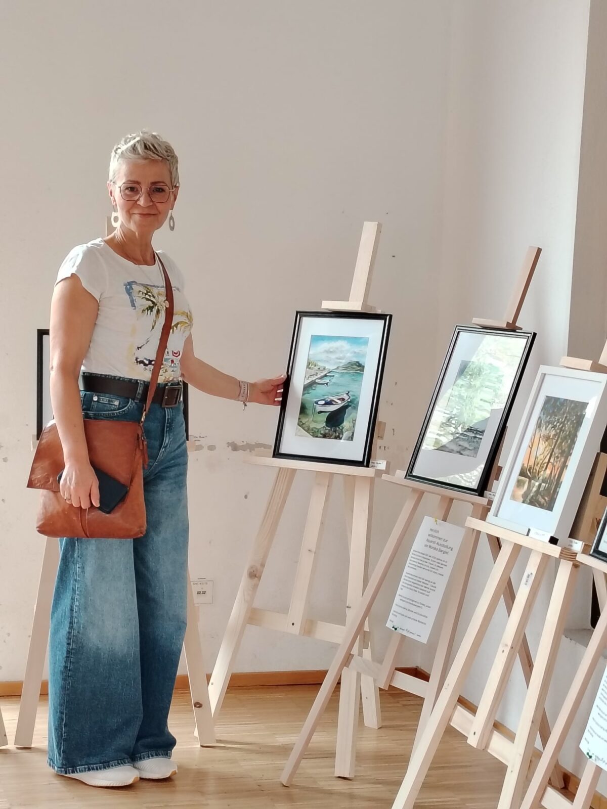 Monika Bargieł bei ihrer Kunstausstellung, stehend neben einer Auswahl ihrer Aquarellwerke