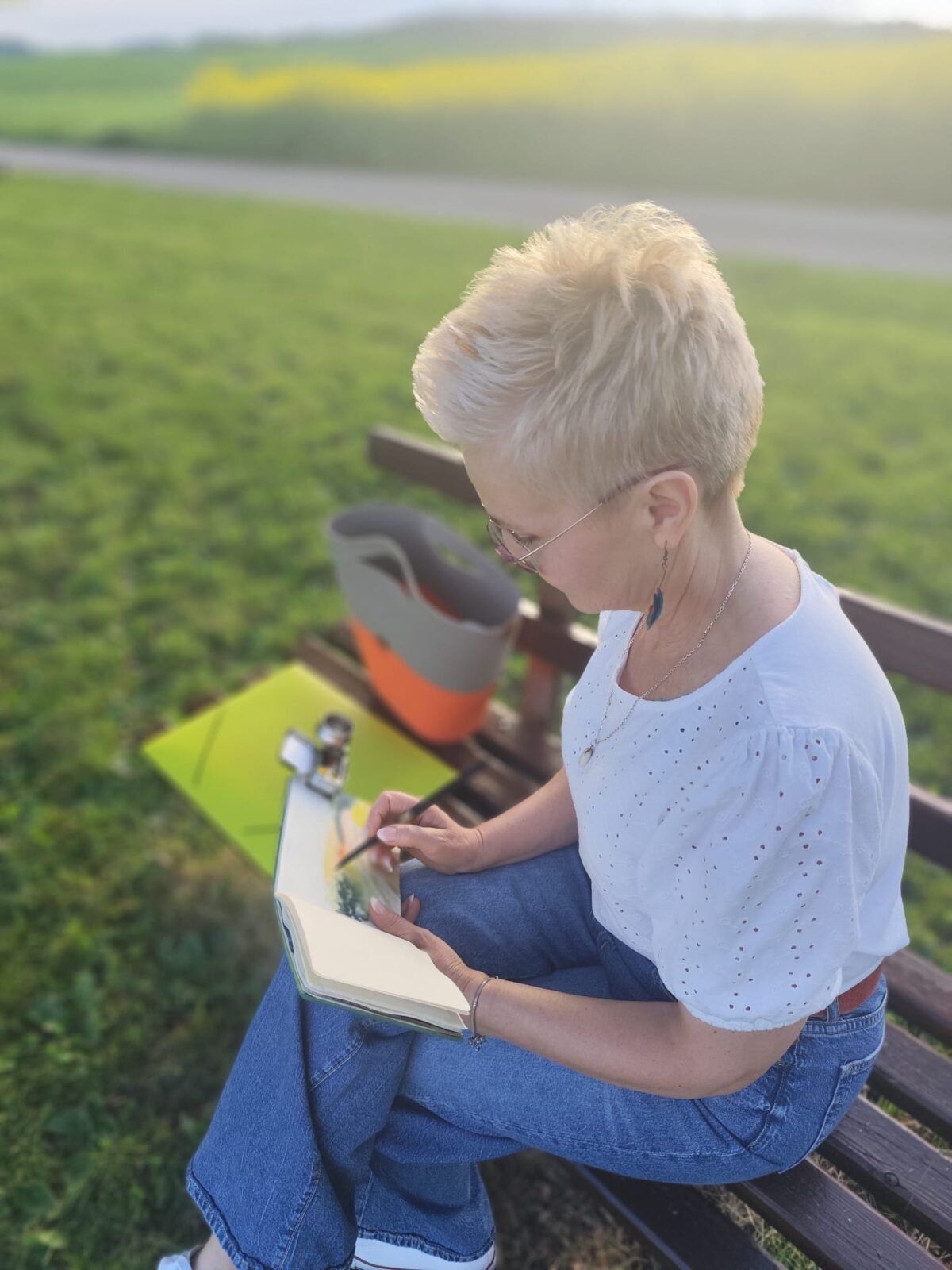 Künstlerin Monika Bargieł beim Entwurf eines neuen Aquarellmotivs auf einer Parkbank.