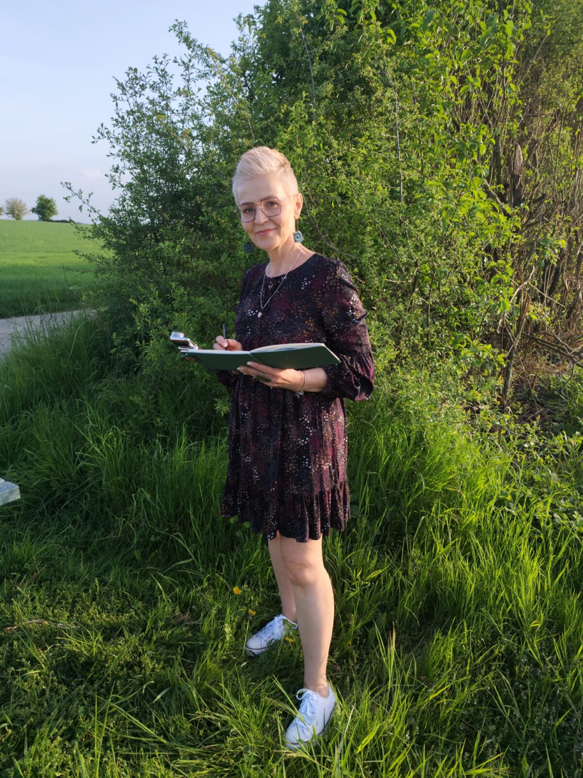 Monika Bargieł beim Skizzieren im Grünen, stehend mit Skizzenbuch in der Natur.